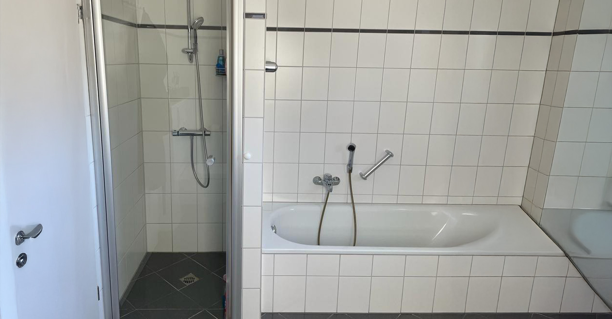 Moderne Badezimmer mit Badewanne und Dusche in hellen Fliesen