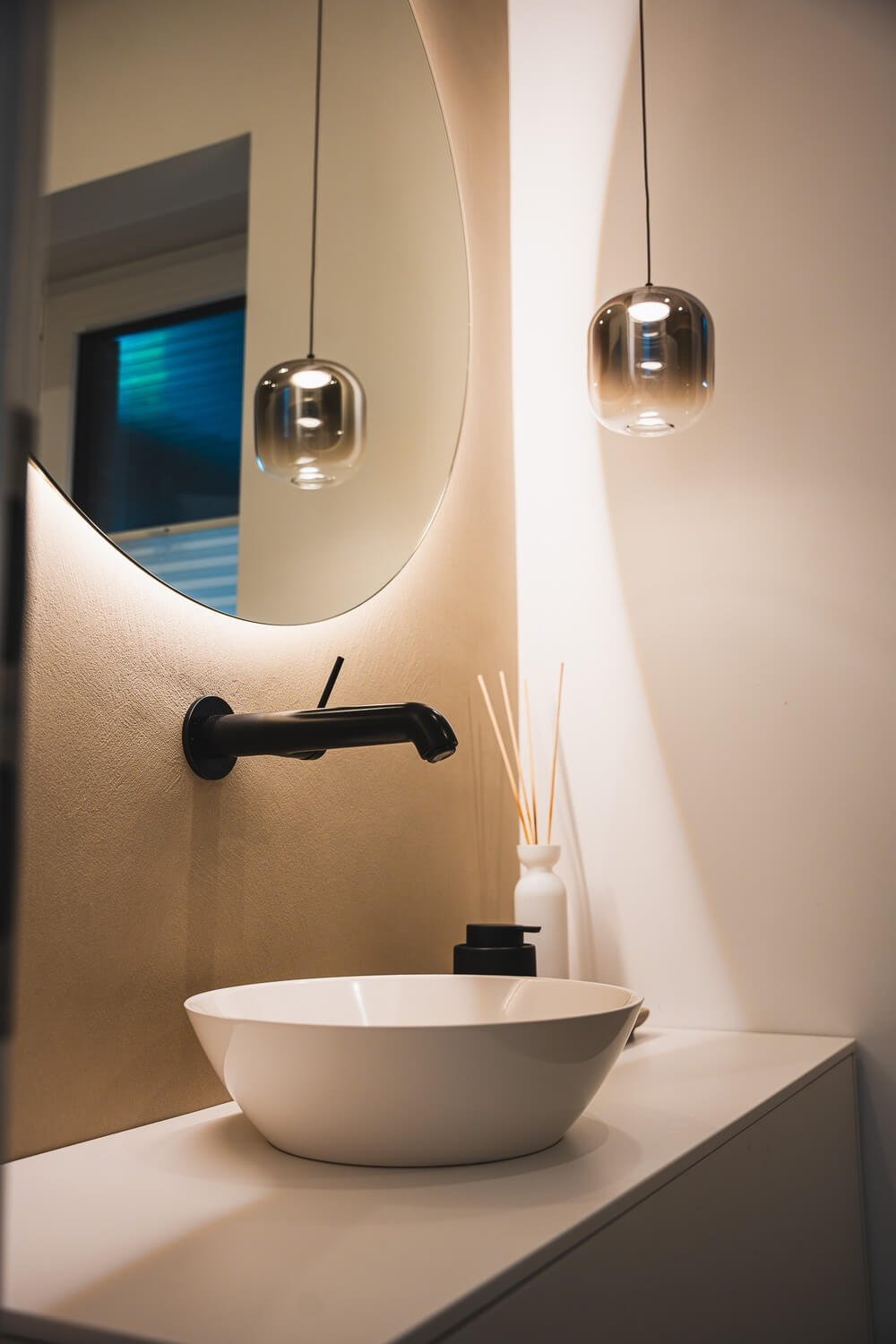 Modernes Badezimmer mit ovalem Spiegel und schwarzer Wasserhahn